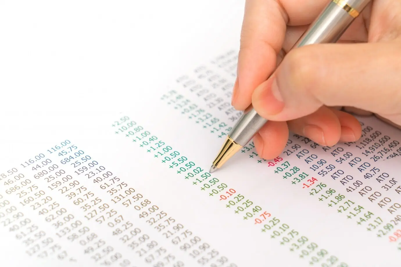 A businesswoman's hand with financial charts and a laptop on the ta