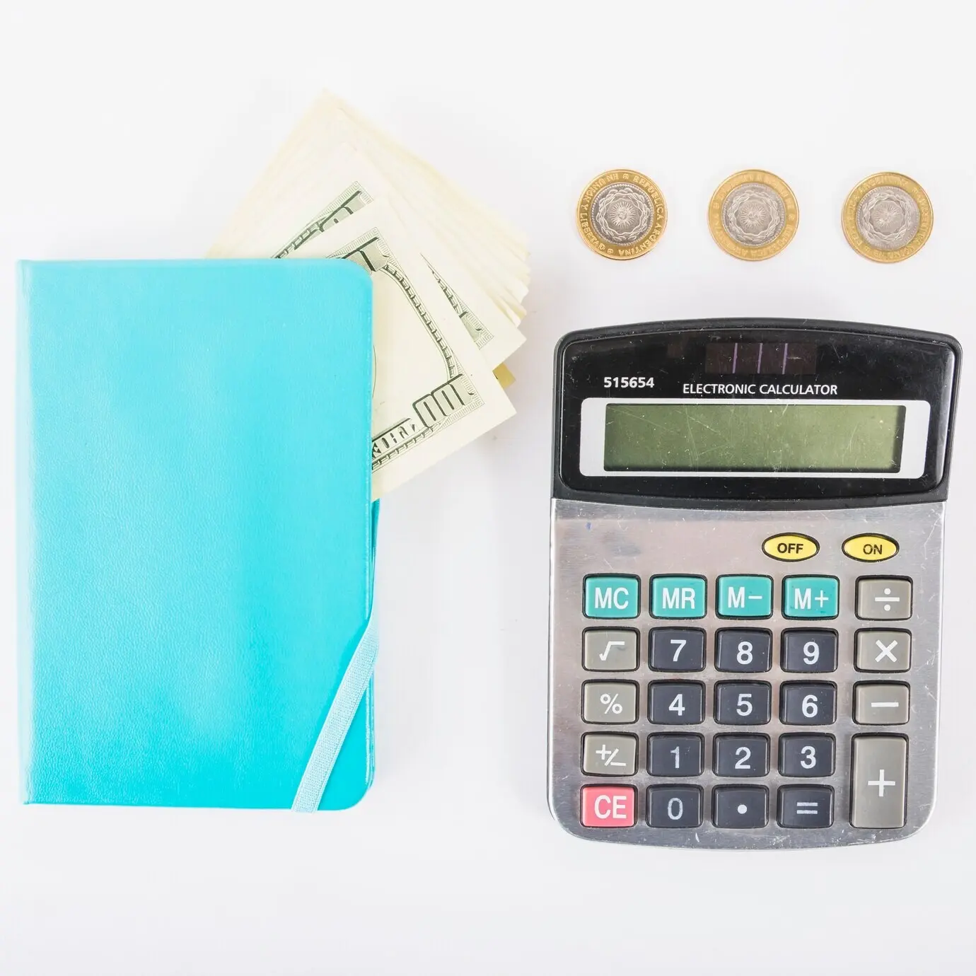 A calculator, money, and a notebook on a table.